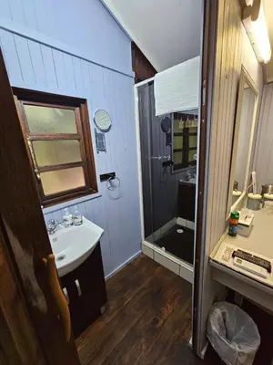 a small bathroom with a sink and a shower at Whispering Creek Mountain Lodge in Magoebaskloof