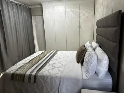 a bedroom with a large bed with white cabinets at Serene Stays Elarduspark in Pretoria