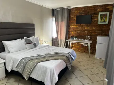 a bedroom with a bed and a television in it at Serene Stays Elarduspark in Pretoria