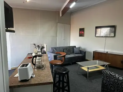 a living room with a couch and a table at Serene Stays Elarduspark in Pretoria