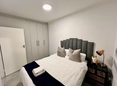a bedroom with a large bed with white sheets and pillows at Suburban Suites at The Reeds in Centurion