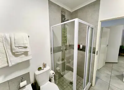 a bathroom with a toilet and a glass shower at Suburban Suites at The Reeds in Centurion