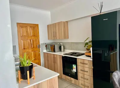 a kitchen with wooden cabinets and a black refrigerator at Suburban Suites at The Reeds in Centurion