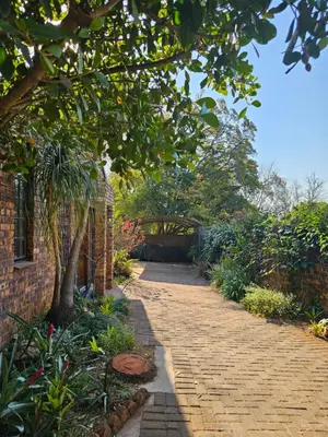 a brick walkway with a tree in a garden at Marilyn's Cottage in White River