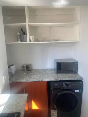 a kitchen with a microwave and a washer and dryer at The Royal Kyota in Sandton