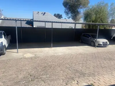 two cars parked in a parking lot next to a fence at The Royal Kyota in Sandton