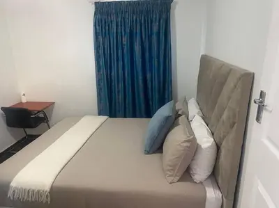 a bedroom with a bed with pillows and a blue curtain at The Royal Kyota in Sandton