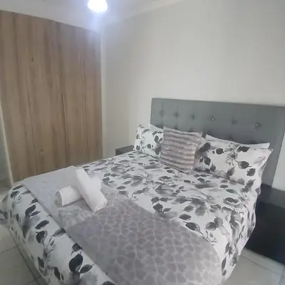 a bed with a black and white comforter and pillows at The Blyde 2-Bed Luxe Apartment in Pretoria