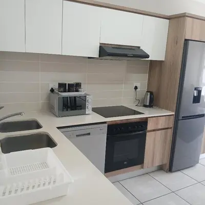 a kitchen with a sink and a refrigerator at The Blyde 2-Bed Luxe Apartment in Pretoria
