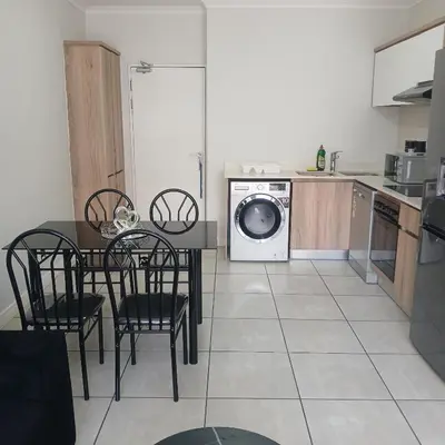 a kitchen with a table and a washing machine at The Blyde 2-Bed Luxe Apartment in Pretoria