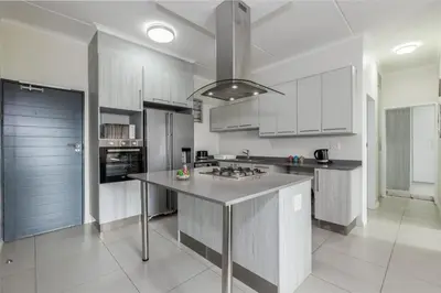 a kitchen with white cabinets and a large island at Fredas Place 92 On New in Midrand