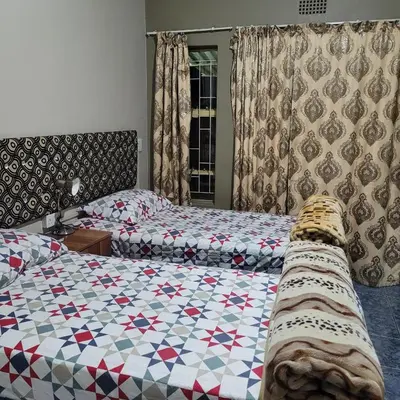 a bedroom with two beds with a quilt on them at Delapaix Guest lodge in Kempton Park