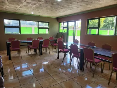 a room with tables and chairs and windows at Delapaix Guest lodge in Kempton Park