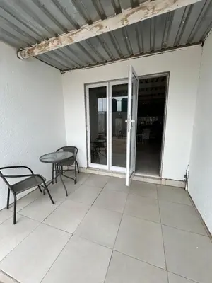 a patio with a table and chairs and a glass door at Riverview Pool Resort and Lodge in Moletlane