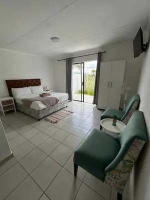 a bedroom with a bed and a table and chairs at Riverview Pool Resort and Lodge in Moletlane