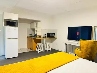a room with a kitchen with a bed and a desk at Busa House Self-Catering Unit in White River