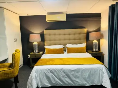 a bedroom with a large bed with yellow sheets and two lamps at Busa House Self-Catering Unit in White River