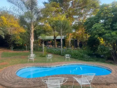 a swimming pool with chairs and a tree at Busa House Self-Catering Unit in White River