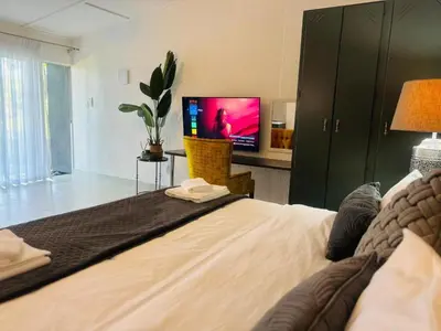 a bedroom with a large bed with a tv on it at Busa House Self-Catering Guest House in White River
