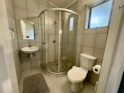 a bathroom with a shower and a toilet and a sink at Busa House Self-Catering Guest House in White River