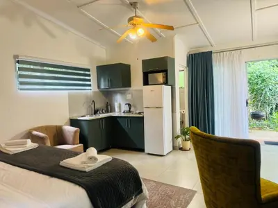 a living room with a bed and a kitchen at Busa House Self-Catering Guest House in White River
