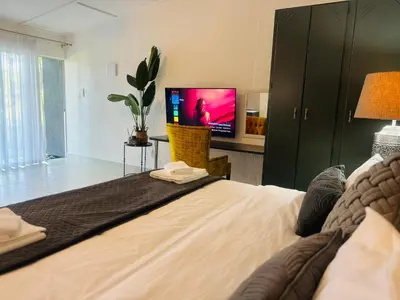 a bedroom with a large bed with a tv on it at Busa House Self-Catering Guest House in White River