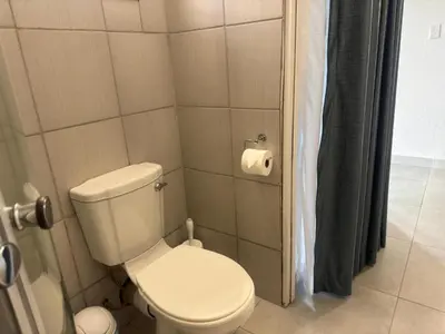 a bathroom with a toilet and a roll of toilet paper at Busa House Self-Catering Guest House in White River