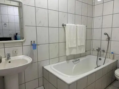 a bathroom with a sink and a tub and a toilet at Busa House - Triple Room in White River