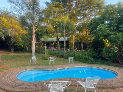 a swimming pool with chairs and a table at Busa House - Triple Room in White River