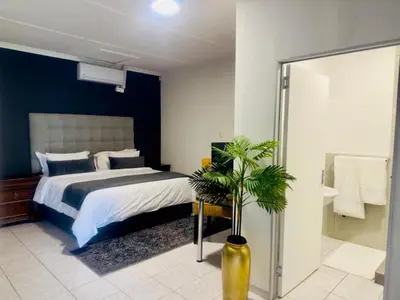 a bedroom with a large bed and a bathroom at Busa House Self-Catering guest house Caravan Park in White River