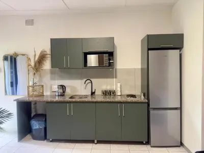 a kitchen with green cabinets and a stainless steel refrigerator at Busa House Self-Catering guest house Caravan Park in White River