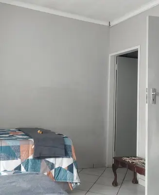 a white bedroom with a bed and a table at Brits Contractors Accommodation in Brits