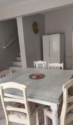 a table with white chairs and a plate on it at Brits Contractors Accommodation in Brits