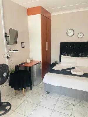 a bedroom with a bed and a desk and a television at Plein On Suid Guesthouse in Polokwane