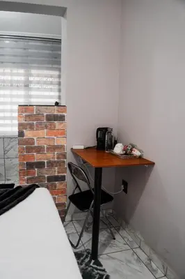 a desk in a room with a brick wall and a bed at Plein On Suid Guesthouse in Polokwane