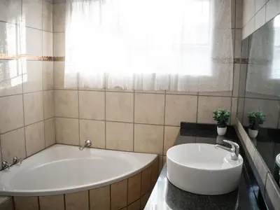 a bathroom with a tub and a sink at Plein On Suid Guesthouse in Polokwane