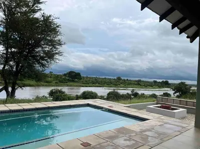 a swimming pool with a view of a river at Beautiful Home Mjejane Private Game Reserve in Hectorspruit