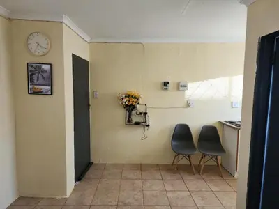 a hallway with two chairs and a clock on the wall at Zone 4 Motel and spa in Polokwane