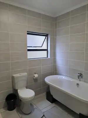a bathroom with a toilet and a tub and a window at Apartment in Kikuyu, Waterfall in Midrand