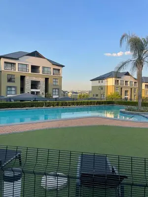 a swimming pool with chairs in front of a house at Apartment in Kikuyu, Waterfall in Midrand