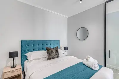 a bedroom with a large bed with a blue headboard at Oku Luxury apartment, Ellipse, Waterfall in Midrand