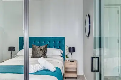 a bedroom with a bed with a blue headboard at Oku Luxury apartment, Ellipse, Waterfall in Midrand