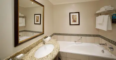 a bathroom with a bath tub and a large mirror at The Ridge Hotel in Witbank