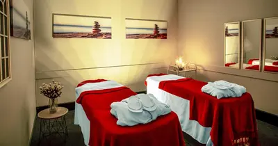 two beds in a room with red and white sheets at The Ridge Hotel in Witbank