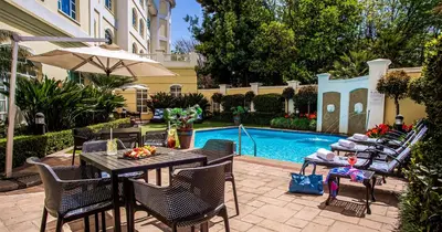 a patio with a table and chairs next to a pool at The Ridge Hotel in Witbank