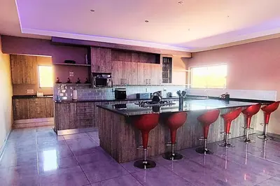 a kitchen with a bar with red bar stools at Zebula Bush Lodge 47 in Moheme