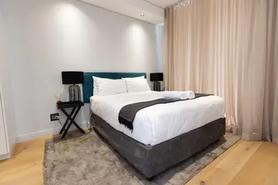 a bedroom with a large bed with white sheets at City Nest - Heart of Waterfall in Midrand