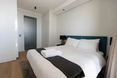 a bedroom with a white bed with two towels on it at City Nest - Heart of Waterfall in Midrand
