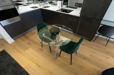 a glass table and two green chairs in a kitchen at City Nest - Heart of Waterfall in Midrand