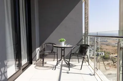 a balcony with three chairs and a table with a potted plant at City Nest - Heart of Waterfall in Midrand
